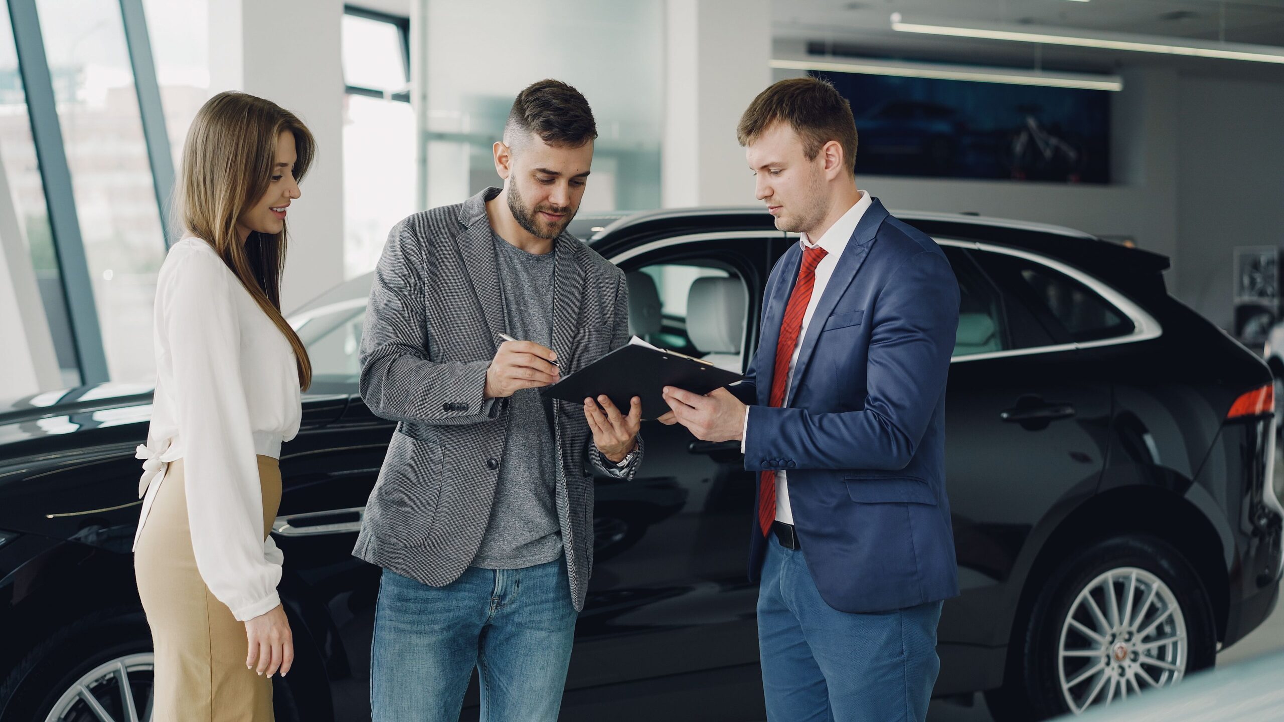 Customers reviewing vehicle paperwork with a dealership adviser, illustrative stock photograph