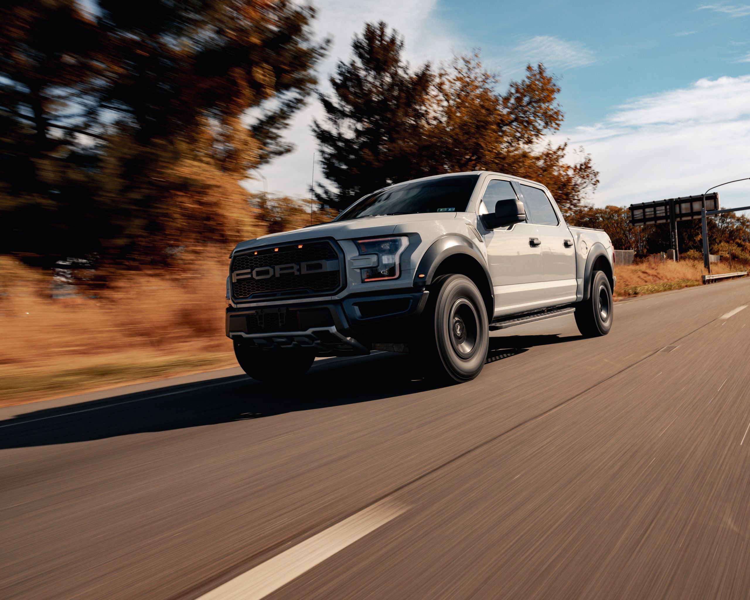 Modern Ford F-150 Raptor driving on an open road, illustrative stock photograph